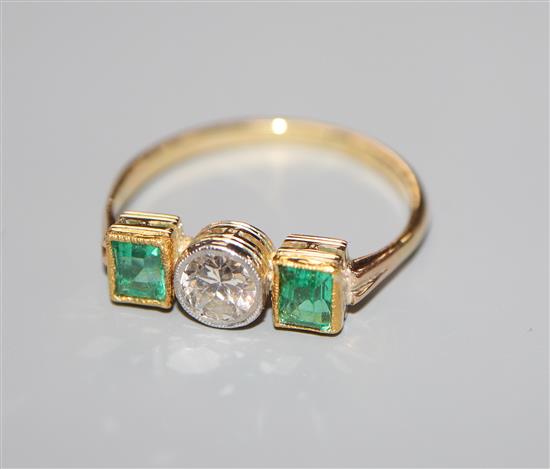 An 18ct and plat. emerald and diamond three stone ring, size K.